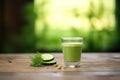 green juice flowing into a clear glass, cucumber slices beside