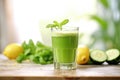 green juice flowing into a clear glass, cucumber slices beside