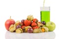 Green juice pouring in to the glass behide red and green apples with orange physalis, purple grapes and red strawberries on white Royalty Free Stock Photo