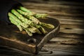 Green juicy asparagus is lying on a wooden board on a brown wooden table Royalty Free Stock Photo