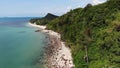 Green jungle and stony beach near sea. Tropical rainforest and rocks near calm blue sea on white sandy shore of Koh Samui paradise