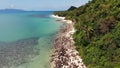Green jungle and stony beach near sea. Tropical rainforest and rocks near calm blue sea on white sandy shore of Koh Samui paradise