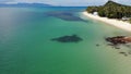 Green jungle and stony beach near sea. Tropical rainforest and rocks near calm blue sea on white sandy shore of Koh Samui paradise Royalty Free Stock Photo