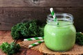 Green kale smoothie in a mason jar on a rustic dark wood background