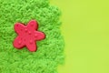 Green kinetic sand with pink starfish plastic sand mold. Kids sensory game, development fine motor skills.