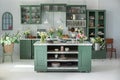 Green kitchen interior with furniture. Stylish cuisine with flowers in vase. Wooden kitchen in spring decor. Cozy home decor. Kitc