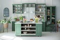 Green kitchen interior with furniture. Stylish cuisine with flowers in vase. Wooden kitchen in spring decor. Cozy home decor. Kitc