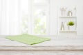 Green kitchen towel on wooden table over blurred window background Royalty Free Stock Photo