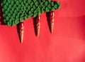 Green knitted handmade Christmas tree with Christmas toys in the form of orange icicles. Beautiful red gradient Christmas