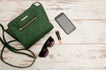 Green ladies handbag, sunglasses, phone and lipstick on wooden background. Fashionable concept Royalty Free Stock Photo