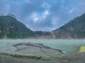 Green lake mirrored with fog above and green cliffs as a background