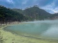 Green lake mirrored with fog above and green cliffs as a background