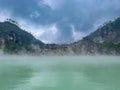 Green lake mirrored with fog above and green cliffs as a background
