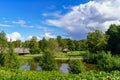 Green landscape with lake, cabins and blue sky with approaching storm,