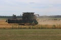 Large Combine Tractor Harvesting Wheat with Stray Bails in the Background