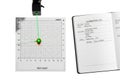 Green laser pointer aiming at target on calibration chart next to open notebook with handwritten notes Royalty Free Stock Photo