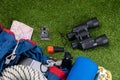 On the green lawn, a set of objects for tourism, binoculars, flashlight, compass, tent, camping Mat.