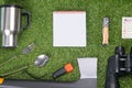 On a green lawn, a tourist`s set, a cup, a fork, a spoon, a knife, a thermos, an ax, binoculars, a flashlight, matches, in the Royalty Free Stock Photo