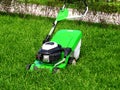 Green lawnmower trimmer in thick dense grass closeup