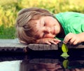 Green leaf-ship in children hand in water, boy in park play with boat in river