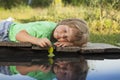 Green leaf-ship in children hand in water, boy in park play with boat in river Royalty Free Stock Photo