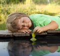 Green leaf-ship in children hand in water, boy in park play with boat in river Royalty Free Stock Photo