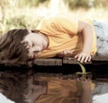 Green leaf-ship in children hand in water, boy in park play with boat in river Royalty Free Stock Photo