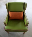 Green leather with pink welt trim armchair with orange throw pillow. Royalty Free Stock Photo