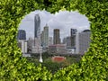 Environtment conservation concept of green leaves frame heart shape space see through to urban cityscape