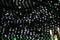 Green LEDs of electric garland against background of blurry white, purple lights Royalty Free Stock Photo