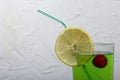 Green lemonade in a glass. Cherry floats in it. Garnished with a slice of lemon. With a straw for a cocktail Royalty Free Stock Photo