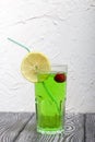 Green lemonade in a glass. Cherry floats in it. Garnished with a slice of lemon. With a straw for a cocktail Royalty Free Stock Photo