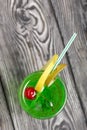 Green lemonade in a glass. Cherry floats in it. Garnished with a slice of lemon. With a straw for a cocktail Royalty Free Stock Photo