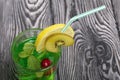 Green lemonade in a glass. It floats cherry and mint leaves. Garnished with a slice of lemon and kiwi. With a straw for a cocktail Royalty Free Stock Photo