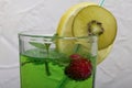 Green lemonade in a glass. It floats cherry and mint leaves. Garnished with a slice of lemon and kiwi. With a straw for a cocktail Royalty Free Stock Photo