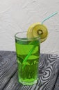 Green lemonade in a glass. Garnished with a slice of lemon and kiwi. With a straw for a cocktail Royalty Free Stock Photo