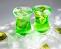 Green lemonade with ice and kiwi slices.Two glass glasses stand on the table and the sun`s rays fall on them Royalty Free Stock Photo