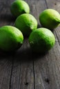 Green lemons on dark wooden surface