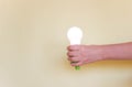 Green Light bulb on yellow background. Hand holds lamp. Free copy space. Concept of new idea, green energy Royalty Free Stock Photo