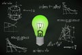 Green lightbulb on blackboard with math calculations