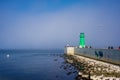 Green lighthouse, fog and blue water in contrasting sunlight Royalty Free Stock Photo