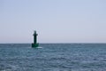 A green lighthouse standing lonely in the middle of the se