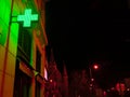 Green lighting cross at a pharmacy shop at night