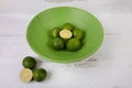 Green lime fruit whole and half slices in a wood bowl and white wood background