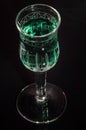 Green liquid in a crystal glass with dark background