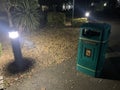 Green Litterbin and a small Black lamp post taken at night Royalty Free Stock Photo