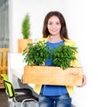 Green living. Attractive young businesswoman standing in modern loft office holding a box with plants. Environmental Royalty Free Stock Photo