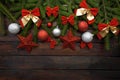 Green living spruce branches on a dark wooden background. New Year background with beautiful balls and red bows and bells. Top vie