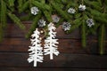 Green living spruce branches on a dark wooden background. New Year background with cones and cardboard Christmas trees. Top view