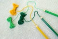 Green, llight green and yellow yarns go from srtands to pencils of the same colors on natural linen cloth